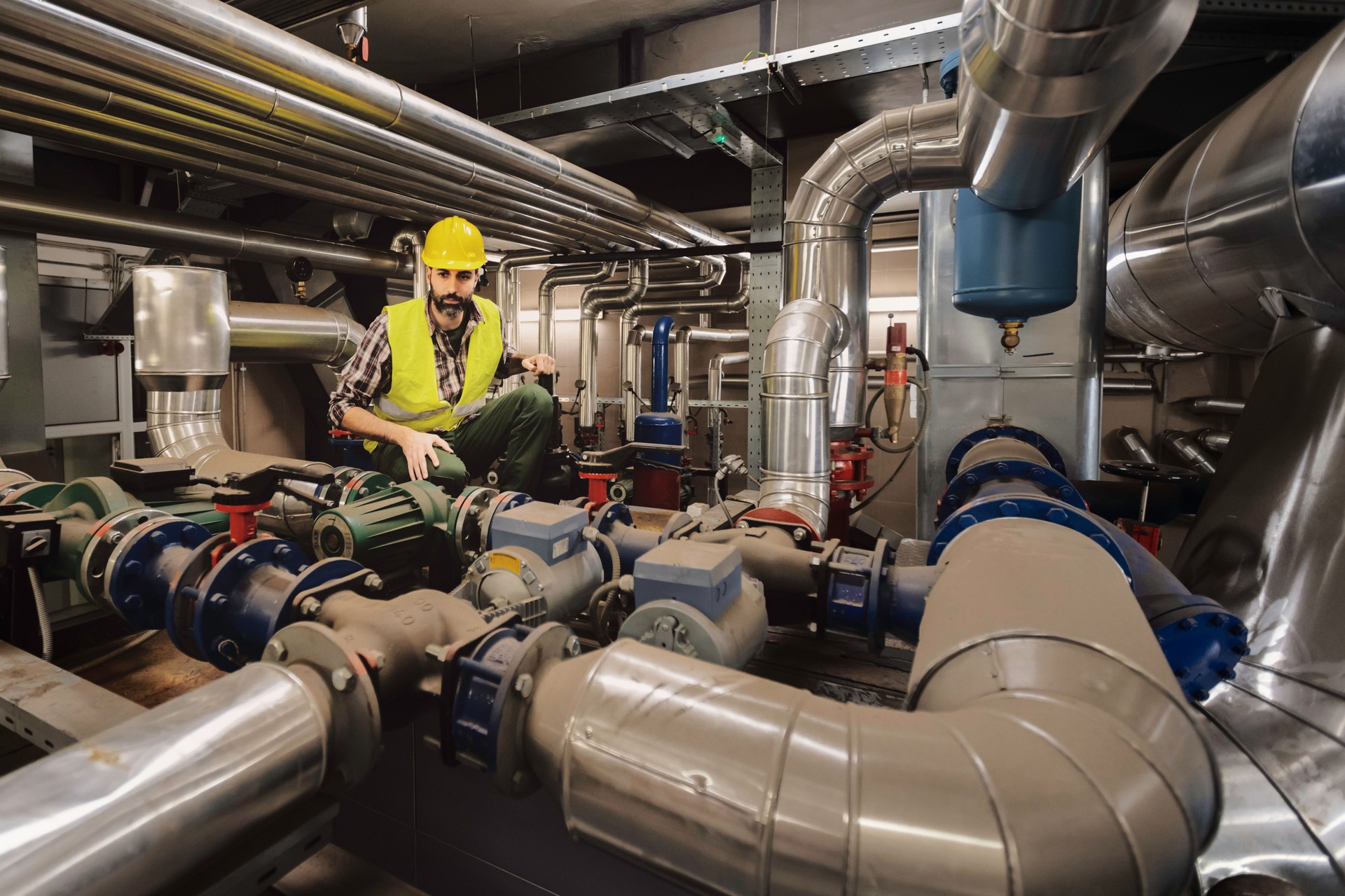 Technician engineer man in uniform with tablet checking and control boiler tanks and liquid pipeline in production line at factory